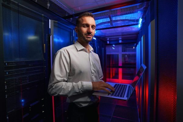 Close up portrait of handsome Caucasian professional it specialist holding laptop in hands